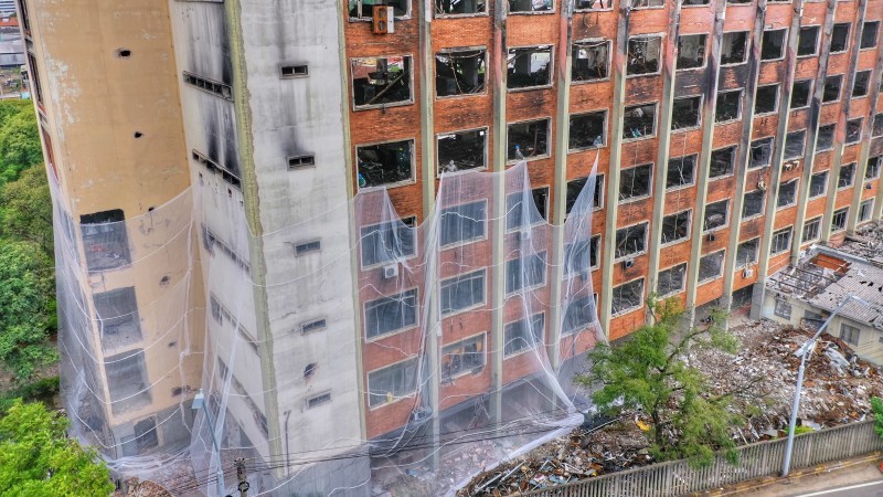 Operários da empresa demolidora passam tela através da abertura das janelas, envolvendo a estrutura até o quarto andar - Foto: Divulgação FBI Demolidora