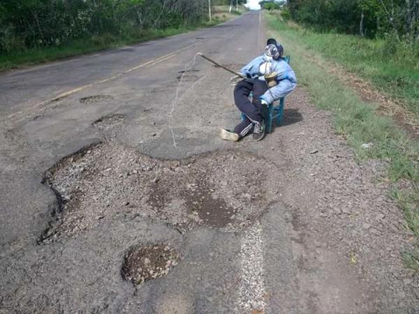 Boneco sentado numa cadeira faz alusão de estar pescando em um dos buracos da pista (Foto: Aline Borba)